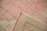 Distressed pink Oushak carpet pile with visible knot heads, revealing hand-knotted foundation.