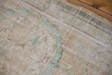 Distressed Oushak rug, showing worn pile with pale beige, apricot, and seafoam tones.