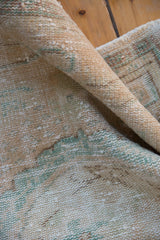 Distressed Oushak rug pile texture in pale beige, seafoam, and apricot.
