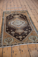 Vintage distressed Oushak runner detail: ivory medallion with hook and latch motifs on chocolate brown field.