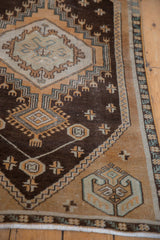 Distressed chocolate brown field with pale rust stepped geometric motifs and visible wear.