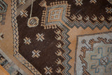 Distressed Oushak rug: chocolate brown field, pale rust geometric motifs, and worn pile.