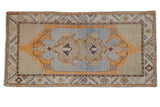 Vintage Oushak rug runner with faded blue medallion, saffron field, and decorative even wear.