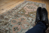 Angled view of a distressed Oushak runner, featuring geometric medallions in faded rose, sage, and charcoal.