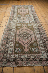 Distressed vintage Oushak runner end, showing fringe and geometric pattern in dusty rose, charcoal.