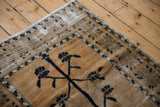 Distressed corner of a vintage Oushak rug with navy tree of life, geometric border, and ivory wear.