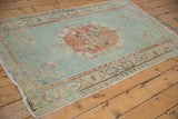 Lower corner of Vintage Distressed Oushak rug, ivory fringe, overcast edge, worn floral border.
