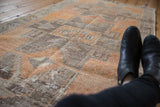 Texture of distressed Oushak runner with primitive geometric pinwheel designs in burnt orange and gray.