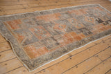 Corner of distressed Oushak runner with geometric border, worn texture, and intact side selvage.