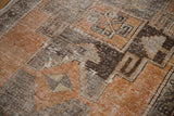 Distressed Oushak runner with geometric burnt orange and charcoal patterns, showing natural wear.