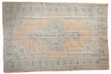 Distressed vintage Oushak carpet with a scalloped medallion, worn saffron field, and faded blue borders, 6'3