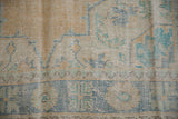 Textured distressed vintage Oushak rug detail with mostly even wear, saffron, and pale blue patterns.