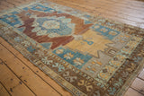 Abrashed field of distressed Oushak runner with copper and saffron tones, blue geometric spandrel.