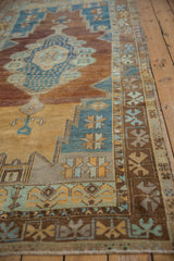 Distressed Oushak runner detail: low pile, geometric border, sky blue, saffron, copper tones.