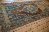 Distressed Oushak rug border with geometric blue, saffron motifs, worn pile revealing foundation.