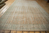 Vintage distressed Oushak rug border detail, featuring faded mint green, apricot, and beige scrolling floral motifs.