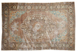 Distressed vintage Oushak rug featuring a scalloped medallion in copper, turquoise, and beige.