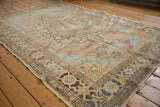 Distressed Oushak rug texture showing knot heads and muted beige, aqua, brown patterns.