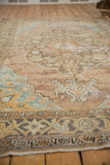 Distressed vintage Oushak rug corner with copper, beige, and aqua palmette spandrel.