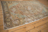 Faded turquoise and brown palmette motifs on a distressed vintage Oushak rug corner.