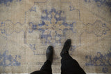 Distressed vintage Oushak rug with even wear, faint foundation, and faded blue pattern.