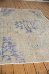 Distressed vintage Oushak rug texture with faint foundation and pale royal blue motifs.