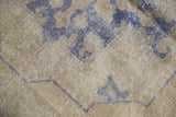 Distressed vintage Oushak rug close-up: worn pile, pale blue motifs, and faint foundation.