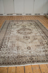 Visible distressed pile texture, chocolate brown border, and natural beige fringe of a vintage Oushak rug.