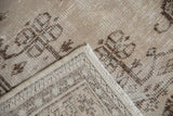 Folded corner shows distressed pile, visible foundation, and reverse weave of Oushak rug.