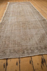 Distressed Turkish Oushak runner, worn pile exposing subtle geometric medallions in beige, sand.