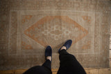Vintage Distressed Oushak rug, elongated medallion, geometric border, soft copper, silver, and ivory tones.