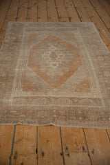 Distressed vintage Oushak rug corner, showing geometric floral border in copper and silver tones.