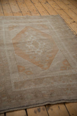 Distressed Oushak rug corner, showing geometric border, stepped overlay, and faded copper tones.