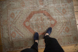 Distressed vintage Oushak rug showing worn terra cotta gul medallion and beige, slate patterns.