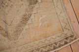 Vintage distressed Oushak runner corner displaying zig-zag border, worn knot heads, and neutral tones.