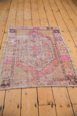 Worn fringe and exposed foundation in pale pink, plum, and ivory on distressed Oushak rug.