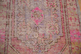 Distressed vintage Oushak rug showing worn pile, visible foundation, and fragmented pink and purple motifs.