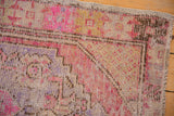 Distressed vintage Oushak rug texture with visible wear, pink, plum, and saffron hues.