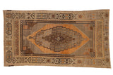 Decorative distressed Oushak rug featuring a stepped medallion, gold, bronze, and charcoal tones.