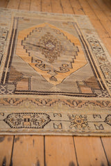 Distressed vintage Oushak rug's geometric gold, charcoal, ivory patterns, and even wear.