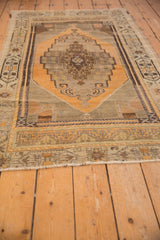 Fringed end of a vintage distressed Oushak rug, with pale bronze and charcoal border detail.
