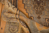 Textured fold of distressed vintage Oushak rug showcasing gold, bronze, and charcoal hues.