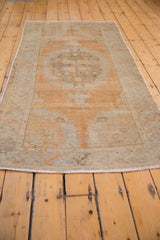Distressed Oushak runner fringe, with abrashed pale orange, ivory, and silver floral designs.
