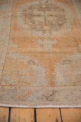 Distressed texture, fringe, and muted tangerine and silver tones on a vintage Oushak rug.