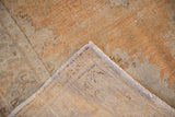Distressed vintage Oushak rug corner, low pile in faded tangerine, exposing hand-knotted foundation.