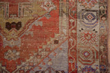 Vintage Oushak rug with abrashed rust, saffron, blue tones, showing wear and side selvage.