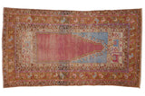 Distressed Turkish Oushak rug with a prayer design in faded purple, sky blue, and saffron yellow.
