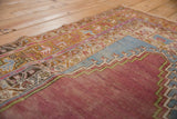 Meandering vine borders and worn texture on the corner of a distressed vintage Oushak rug.