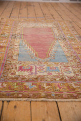 Low angle view of a vintage Oushak rug's worn pile and meandering vine and blossom borders.
