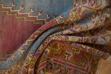 A soft fold reveals the distressed texture and layered palette of a vintage Turkish Oushak rug.
